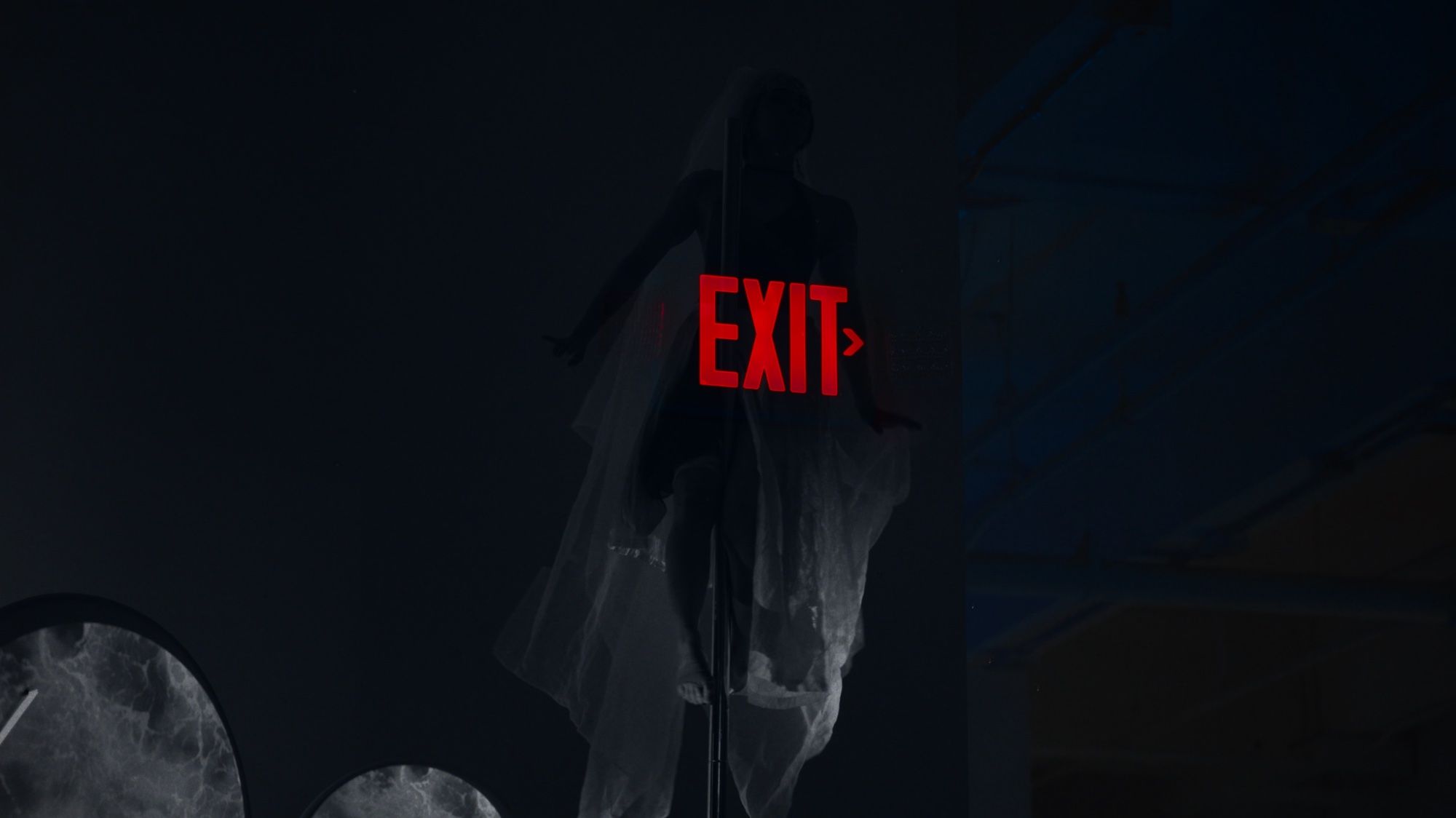 A red EXIT sign above a figure in white fabric.