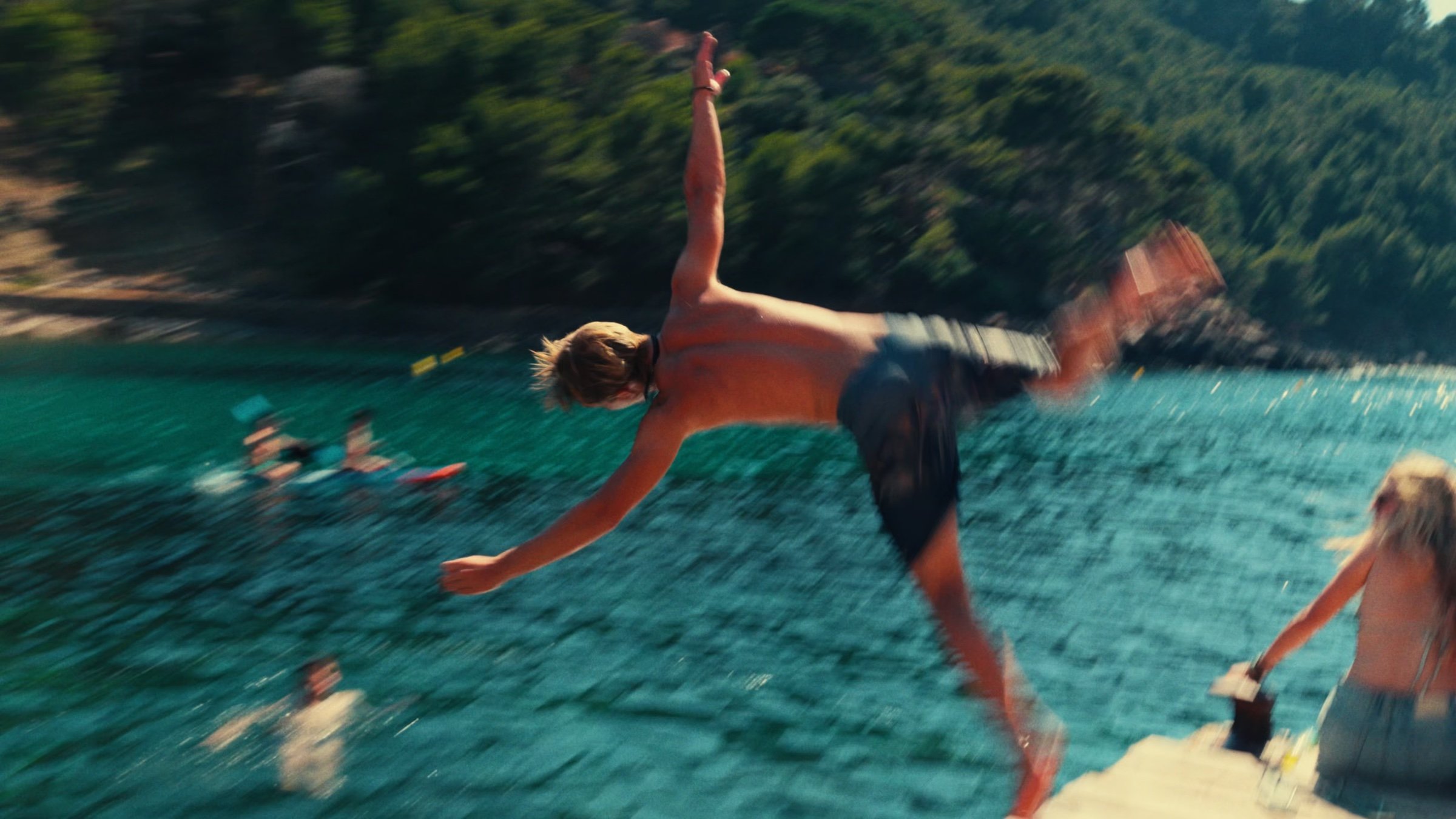 A friend flips off a jetty into turquoise water.