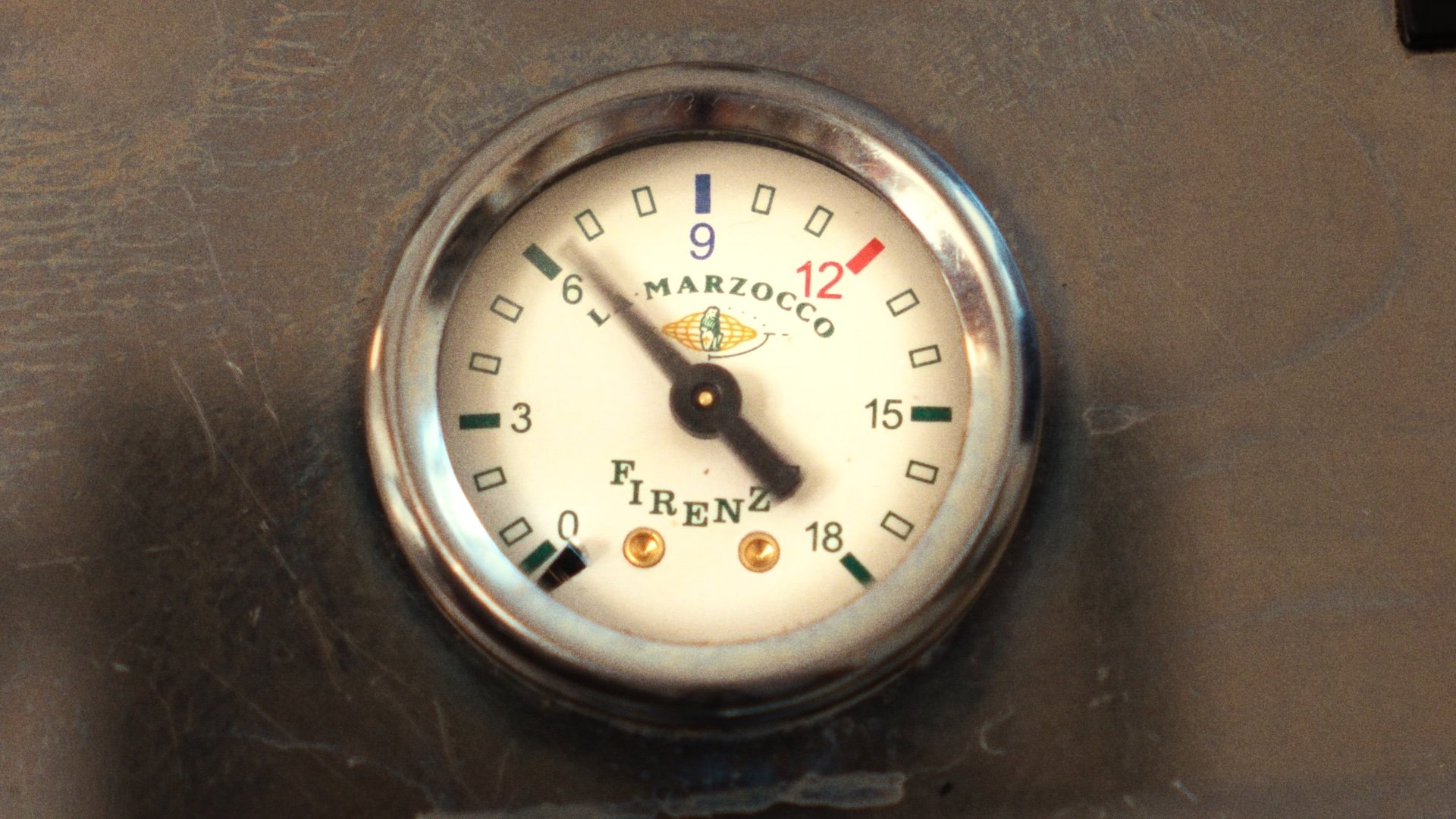 Close-up of an espresso machine's pressure gauge.