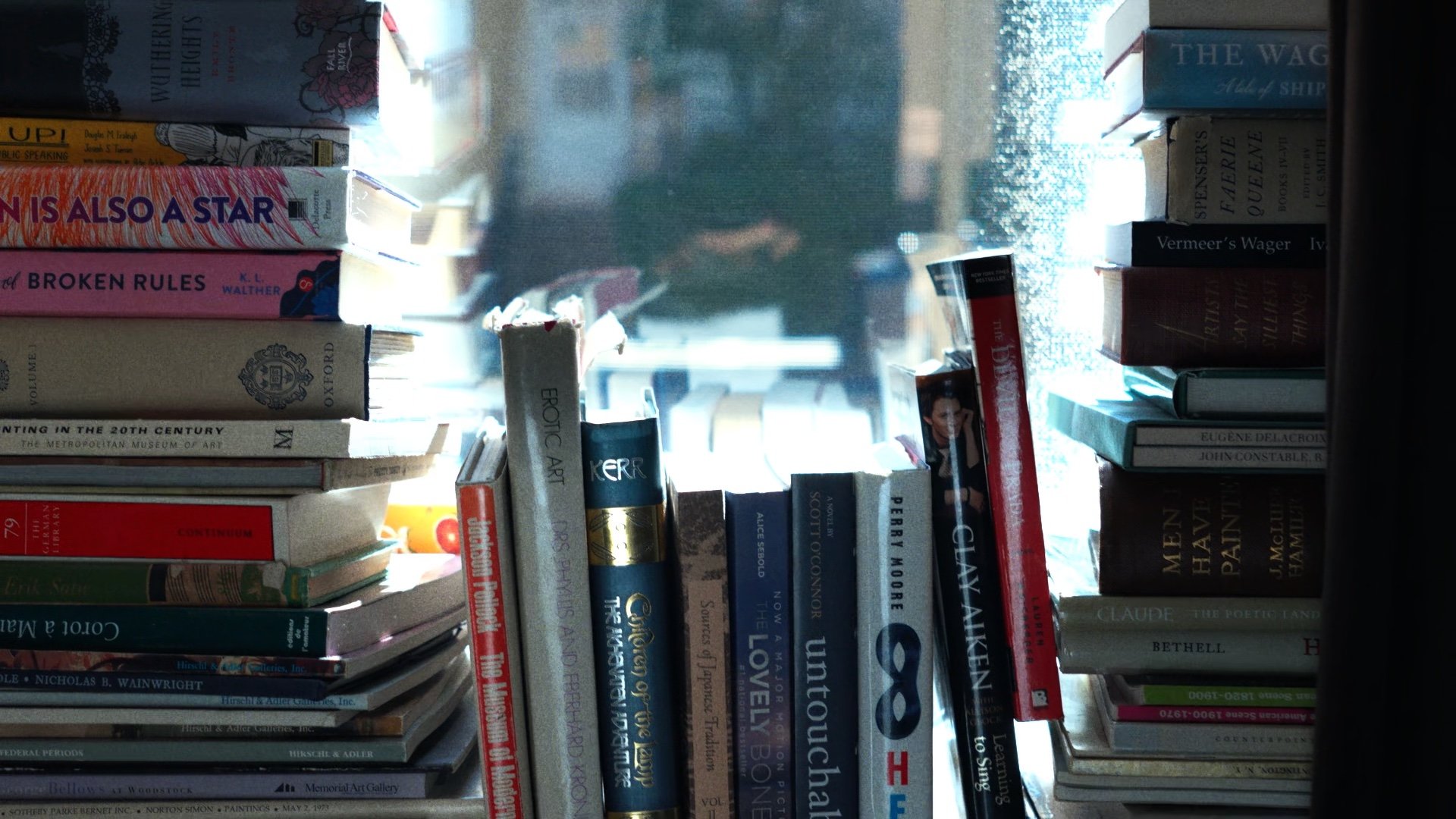 Stacked books beside a bright window.
