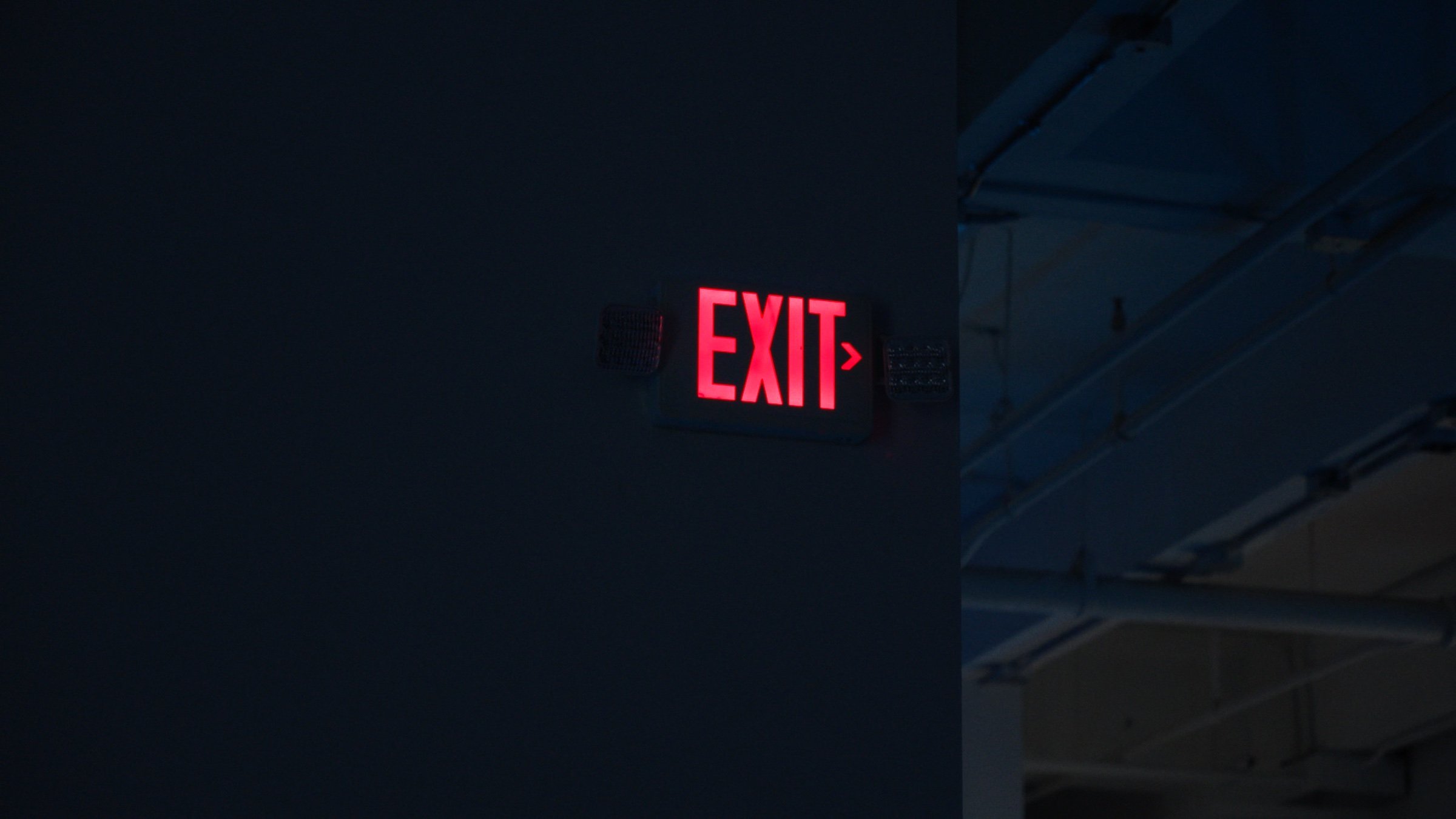 A red EXIT sign in a dark industrial space.
